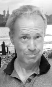 Black and white head shot of PG Somerset with the Thames foreshore in the background